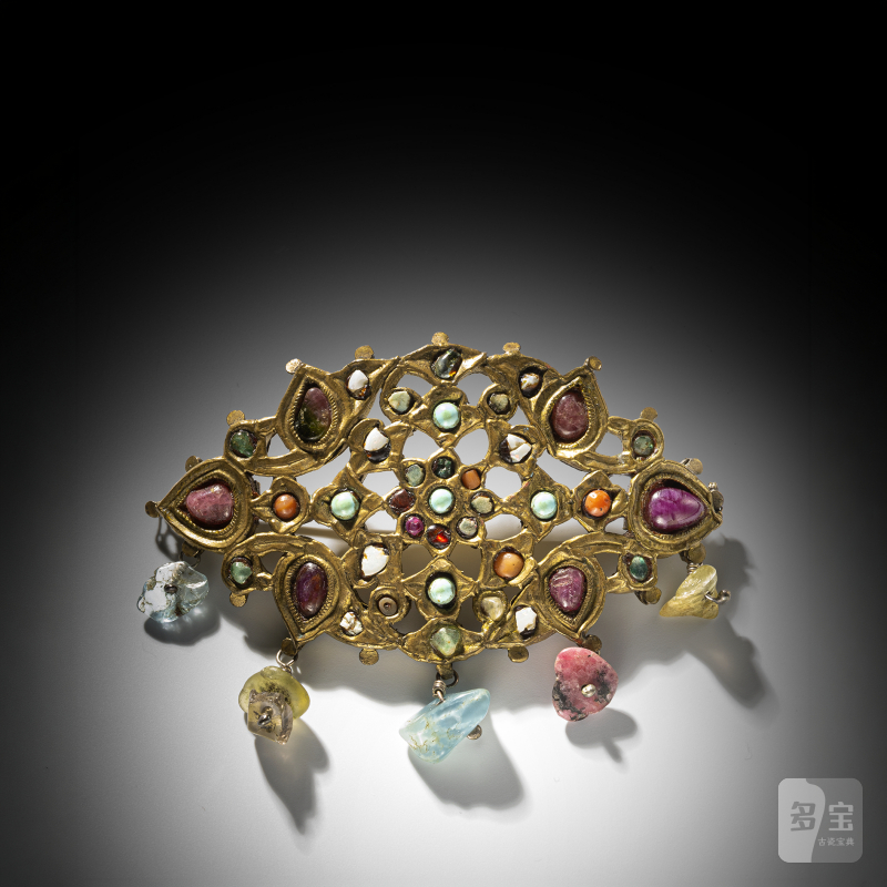 A gemstone-inlaid plaque reworked as a brooch